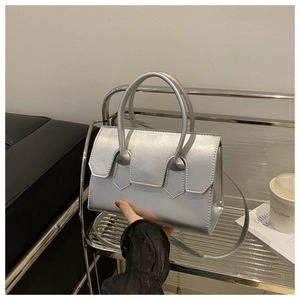 Détail d'un sac à main argenté métallisé avec double poignée et bandoulière fine