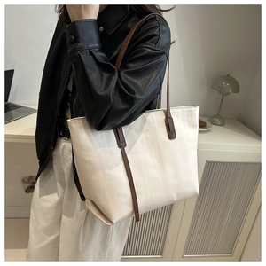 Close-up of minimalist tote bag with beige textured body and dark brown leather straps