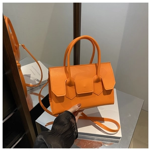 Détail du sac à main orange en cuir avec poignées cylindriques et fermoir décoratif