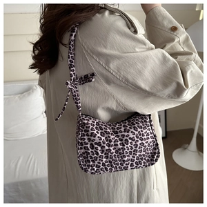 Leopard print tote bag detail showing knotted shoulder strap and zipper closure on a shoulder
