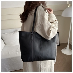 Detail of black tote bag with wave texture carried by a model in a minimalist home setting