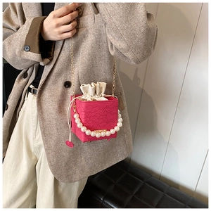Detail of fuchsia bucket bag featuring pearl handle and embossed floral texture