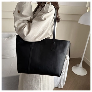 Detailed texture of black leather tote bag with elegant vertical grain and slim shoulder straps