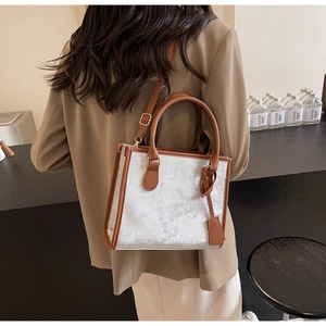 Detail of silver velvet tote bag with brown leather handles and adjustable crossbody strap