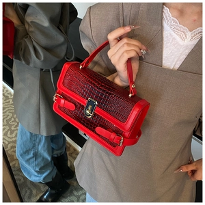 Detailed view of red crocodile pattern handbag with elegant gold metal lock and handle