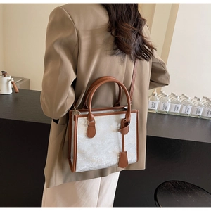 Detail of silver tote bag with brown faux leather trim and detachable shoulder strap