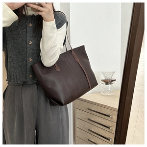Detailed view of the dark brown leather tote bag with long handles and a minimalist design