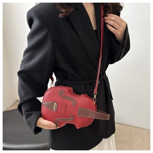 Creative violin shaped crossbody bag in red leather worn with a black blazer