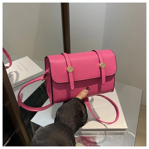 Détail du petit sac carré rose vif avec boucles dorées et fine bandoulière en cuir