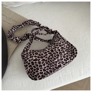 Detail view of leopard print canvas bag with unique ruffled strap and zipper closure