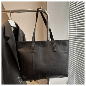 Detail of black tote bag showing subtle vertical wave texture and sleek shoulder straps