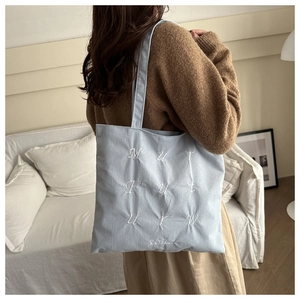 Gros plan sur le sac fourre-tout en velours côtelé bleu clair avec broderie blanche