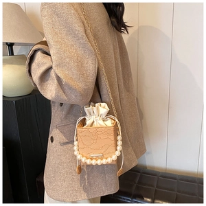 Detail of crossbody bag with pearl handle, lace texture and golden chain strap