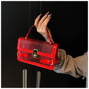 Detailed view of red crocodile embossed leather texture and gold twist-lock on handbag