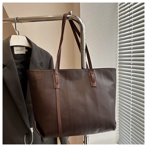 Detail view of brown faux leather tote bag texture hanging with professional blazer