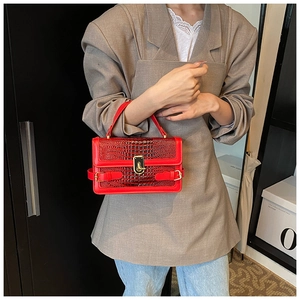 Macro detail of red crocodile texture PU leather handbag with elegant golden metal clasp