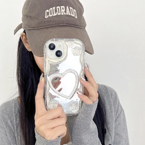 Custodia iPhone specchio cuore argento con rose 3D e bordi a onde tenuta da modella
