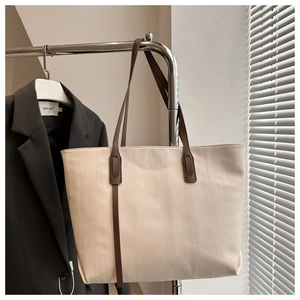 Macro shot of cream-colored tote bag with fine vertical ripple texture and thin brown strap