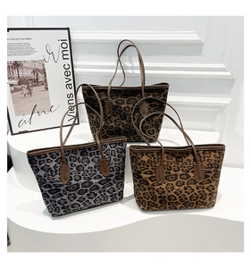 Close-up of three leopard print tote bags in grey and brown tones on a white display stand