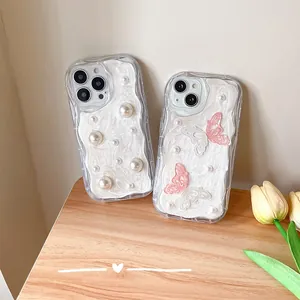 Detail of cream glue texture with pearls and butterflies on iPhone cases
