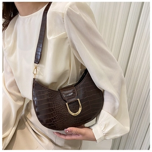 Detailed side view of a brown crocodile-patterned crescent underarm bag with gold D-buckle