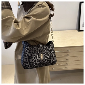 Détail du sac léopard avec boucle dorée et bandoulière en chaîne métallique chic