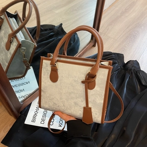 Silver textured tote bag with brown leather handles and adjustable shoulder strap