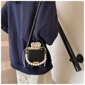 Detail of black pearl bucket bag with matte leather finish and elegant chain strap