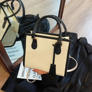 Classic cream and black contrast tote bag with adjustable strap in a stylish setting
