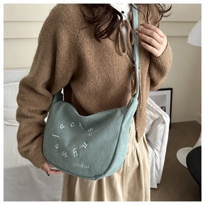 Detail of light green corduroy crossbody bag with white letter embroidery for daily commute