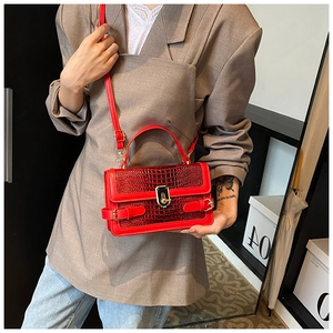 Detail of red crocodile texture handbag with gold metal lock and adjustable shoulder strap