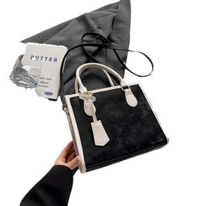 Minimalist black and white color-block tote bag with dual handles and crossbody strap