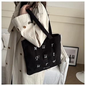 Texture détaillée d'un sac cabas en velours côtelé noir avec broderie sur un trench
