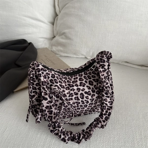 Fashionable leopard print shoulder bag with ruffled handle and tie details in cozy setting