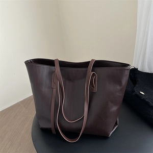 Minimalist large dark brown tote bag in textured PU leather on a display pedestal