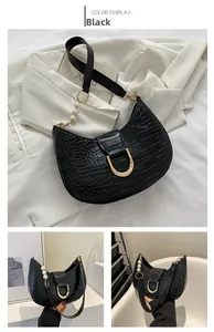 Detail of black crocodile texture bag with gold D-ring buckle and pearl chain