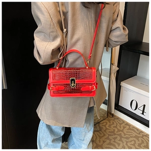 Detail of red crocodile texture handbag with golden twist lock on a beige blazer