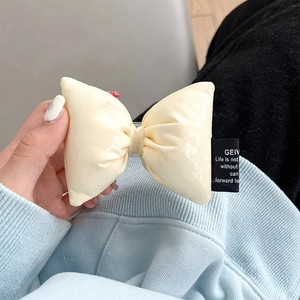 Close-up of cream faux leather bow charm with soft padding and premium stitched label