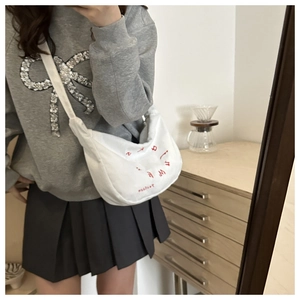 White corduroy crossbody crescent bag with red letter embroidery worn by model