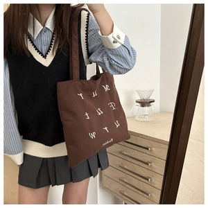 Detail of large brown corduroy tote bag with white letter embroidery for school commute