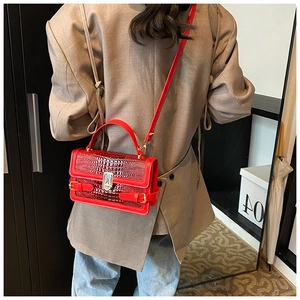 Detail of red crocodile texture crossbody bag with gold twist lock and adjustable strap
