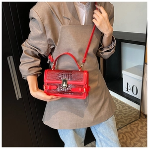 Detailed macro view of the red crocodile textured shoulder bag with a gold square buckle