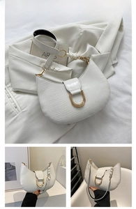 Detail of white half-moon bag featuring crocodile texture and elegant pearl strap