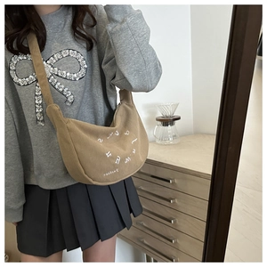 Detail of khaki corduroy crescent bag with letter embroidery in a lifestyle setting