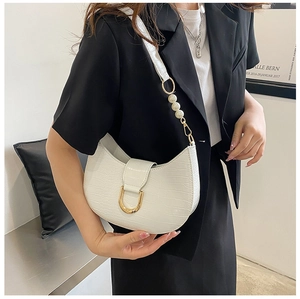 Detail of white crocodile pattern half-moon bag with gold buckle and pearl strap decor