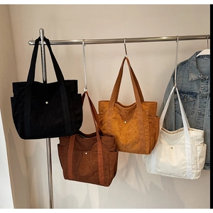 Detail of four colorful corduroy tote bags with snap pockets on a metal hanger