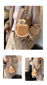 Detail showing lace-patterned bucket bag with decorative pearl handle and drawstring lid