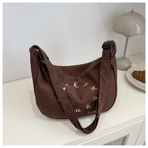Detail of brown corduroy hobo bag with white circular embroidery and adjustable strap