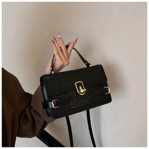 Detail of elegant black crocodile pattern textured PU leather bag with gold swivel lock