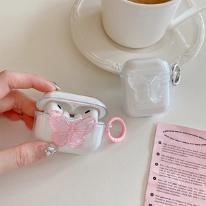 Macro shot of clear AirPods case featuring pink and white resin butterfly charms with hooks